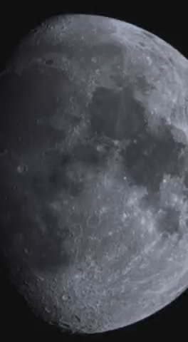 Auto-generated description: A detailed view of the moon's surface, highlighting its craters and dark patches.